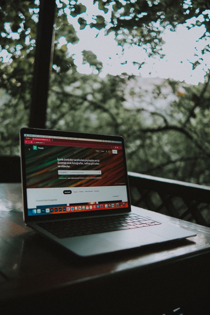The Art of Drawing Readers In: Your attractive post title goes here Open laptop showing a website screen on a wooden table in an outdoor terrace setting.